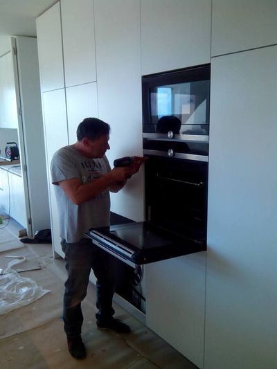Técnico de electrodomesticos da StandAudio a montar um forno encastrável numa cozinha