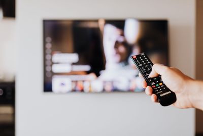 Mão a segurar um comando Samsung apontado para uma televisão